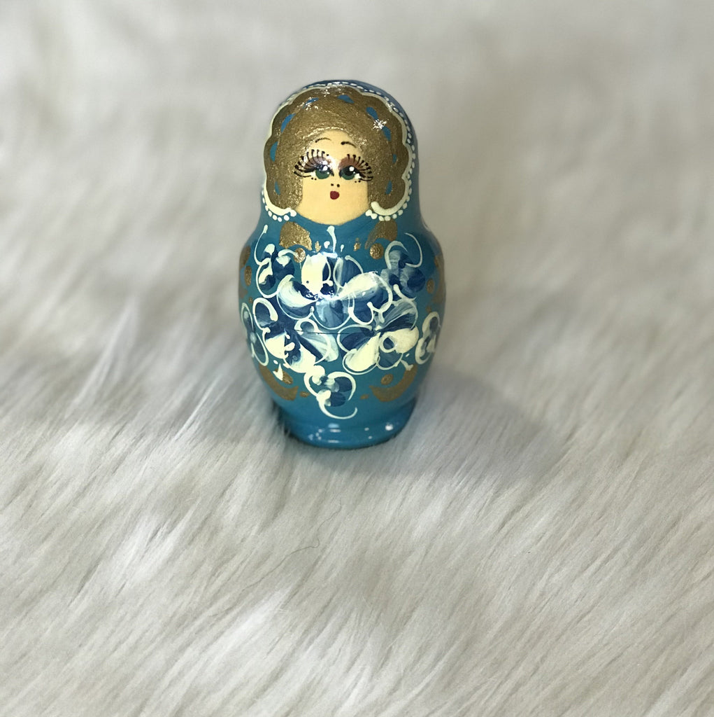The sweetest set of 5 bright blue wooden Russian "Matryoshka" nesting dolls with gold, white, and blue hand-painted faces and floral detail. Largest doll measures just 3.5" tall and 2" wide. Faded "Made in Russia" sticker on bottom"