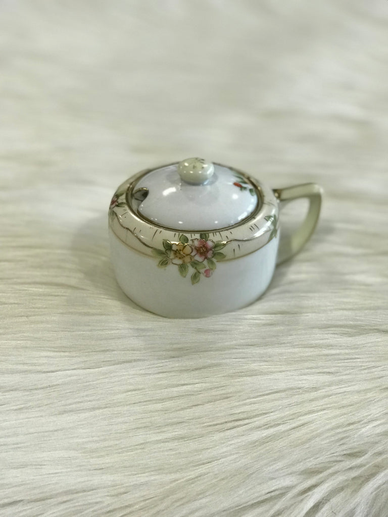 A vintage, lidded Nippon porcelain sugar bowl with hand-painted pink, yellow, green, and gold floral detailing.
